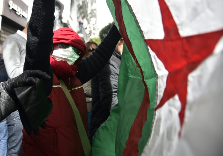جزائري يرفع علم بلاده احتجاجاً على ترشّح الرئيس عبد العزيز بوتفليقة لولاية خامسة خلال تظاهرة في الجزائر العاصمة في 24 شباط/فبراير 2019.