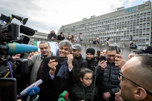 المعارض الجزائري رشيد نكاز يقف في جنيف مع أنصار له أمام المستشفى الذي يرقد فيه الرئيس الجزائري عبد العزيز بوتفليقة