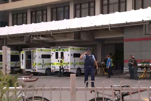 لقطة من تلفزيون نيوزيلندي يظهر فيها ضابط في الشرطة وخلفه سيارات إسعاف أمام مستشفى