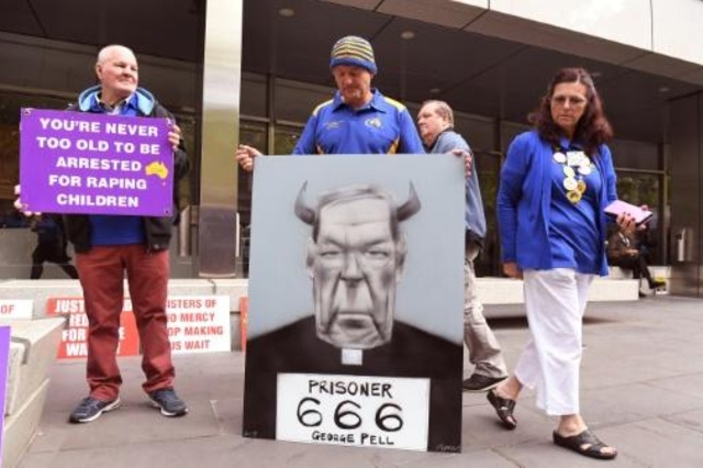 ناجون من اعتداءات في الكنيسة يحملون لافتات تندّد بالكاردينال الاسترالي جورج بيل خارج محكمة كونتي في ملبورن في 13 آذار/مارس 2019.