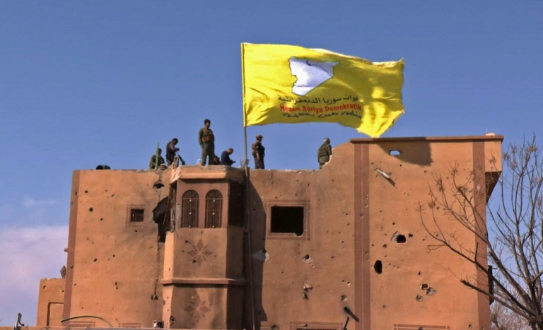  راية قوات سوريا الديموقراطية الصفراء مرفوعة فوق مبنى في الباغوز