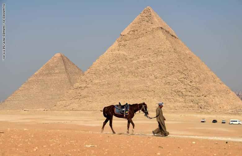 رجل مع حصانه يمر امام اهرامات الجيزة