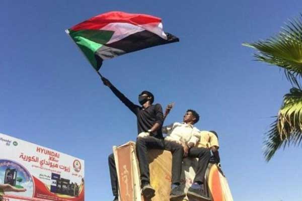  متظاهر يرفع العلم السوداني خارج مقر القيادة العامة للجيش في الخرطوم بتاريخ 7 إبريل 2019