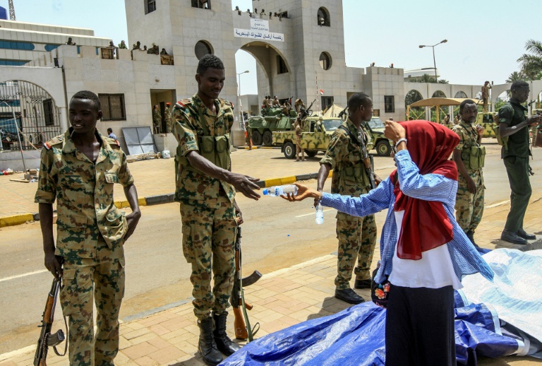 سودانية تقدم قارورة ماء لعسكري أثناء تجمع أمام مقر قيادة الجيش بالخرطوم في 12 نيسان/ابريل 2019