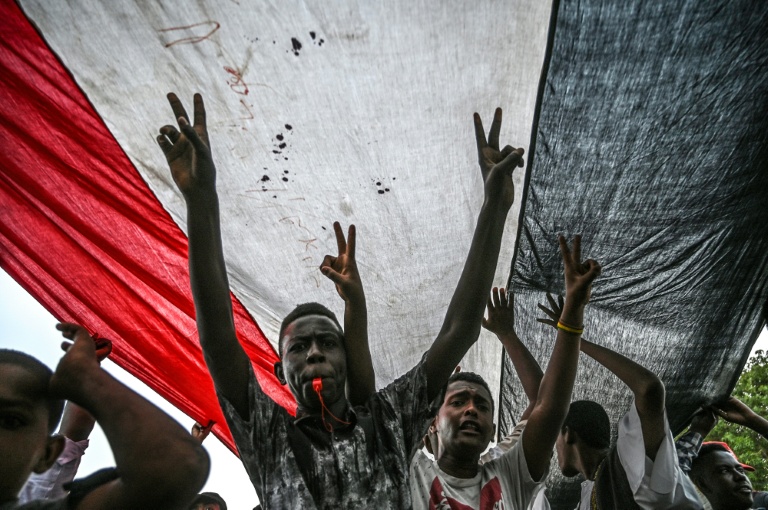 متظاهرون سودانيون يهتفون ويرفعون علامة النصر خلال تجمع خارج مقر القيادة العامة للجيش السوداني في الخرطوم بتاريخ 18 ابريل 2019