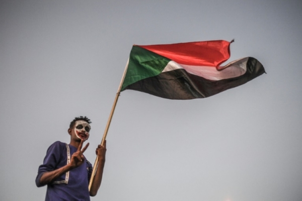 متظاهر سوداني يلوّح بعلم بلاده أمام مقرّ القيادة العامة للجيش في الخرطوم في 20 أبريل 2019