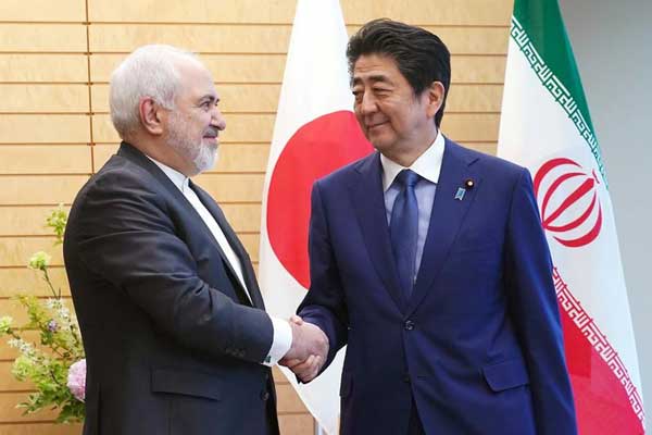 رئيس وزراء اليابان شينزو آبي يصافح وزير الخارجية الإيراني محمد جواد ظريف في طوكيو اليوم الخميس