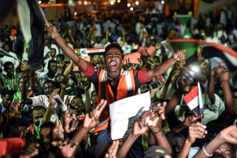 محتجون سودانيون يلوحون بالأعلام وشارات النصر خلال اعتصامهم أمام مقر الجيش في الخرطوم في 19 ايار/مايو 2019