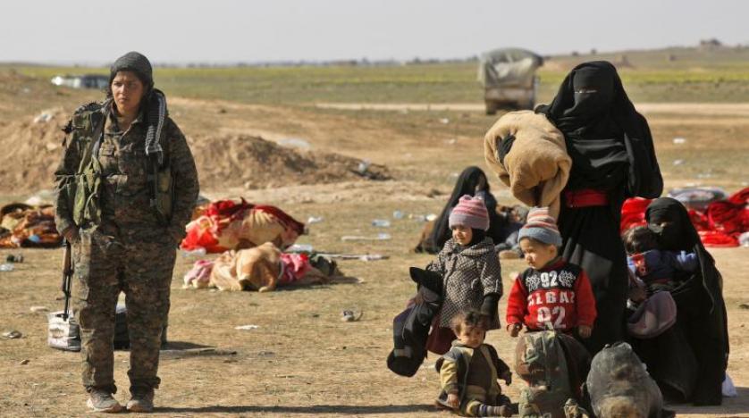 عضو من وحدة حماية المرأة الكردية (يسار) ونساء يهربن من مقاطعة باغوز آخر معاقل «داعش» بدير الزور السورية (أ.ف.ب)