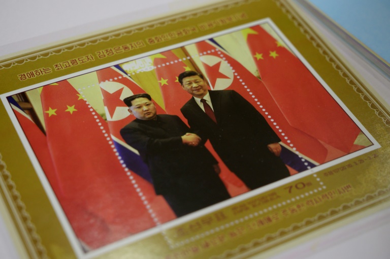 متجر في بيونغ يانغ يعرض طابعا بريديا تذكاريا يحمل صورة الزعيم الكوري الشمالي كيم جونغ أون (يسار) مصافحا الرئيس الصيني شي جينبينغ في 18 يونيو 2019