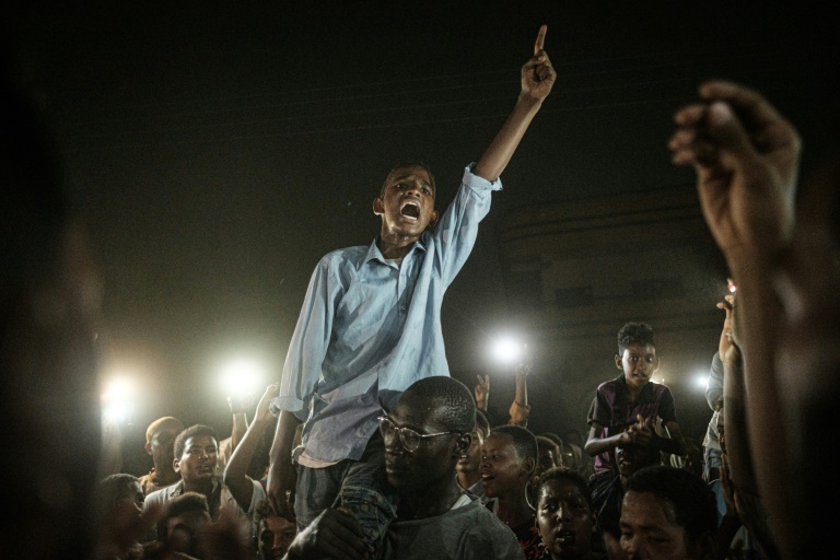 متظاهرون يرددون هتافات خلال تظاهرة ليلية على أضواء هواتفهم المحمولة، في الخرطوم في 19 حزيران/يونيو 2019