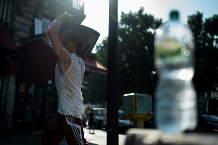 عامل في ورشة بناء إلى جانب زجاجة مياه أثناء موجة الحرّ التي تضرب أوروبا في صورة التُقطت في باريس في 26 يونيو 2019