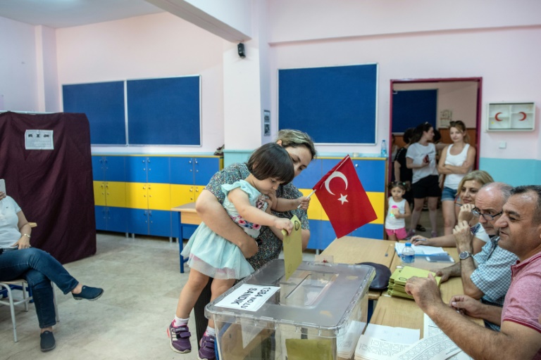 امرأة تحمل طفلتها تدلي بصوتها في الانتخابات البلدية في اسطنبول في 23 يونيو 2019