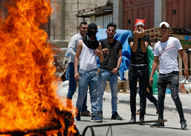 فلسطينيون في 24 يونيو 2019 قرب مدينة الخليل في الضفة الغربية قرب إطار مشتعل خلال احتجاجات على ورشة العمل الأميركية 