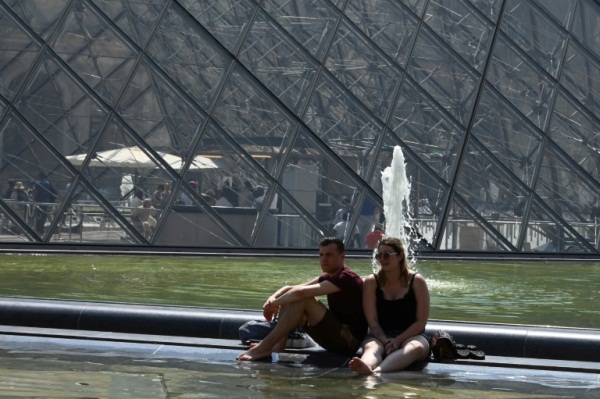 سياح أمام حوض المياه قرب متحف اللوفر في باريس في 26 يونيو 2019 