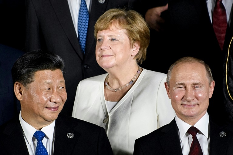 المستشارة الألمانية أنغيلا ميركل إلى جانب الرئيسين الروسي والصيني خلال التقاط صورة جماعية في قمة العشرين في أوساكا في 28 يونيو 2019 