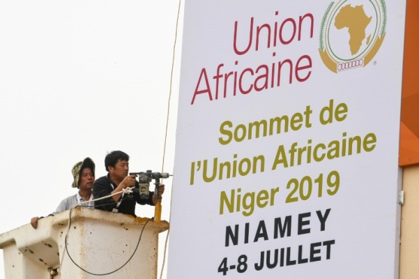 عمال يثبتون ملصقا للقمة الافريقية العادية الـ 35 في قصر المؤتمرات بنيامي عاصمة النيجر في 4 يوليو 2019