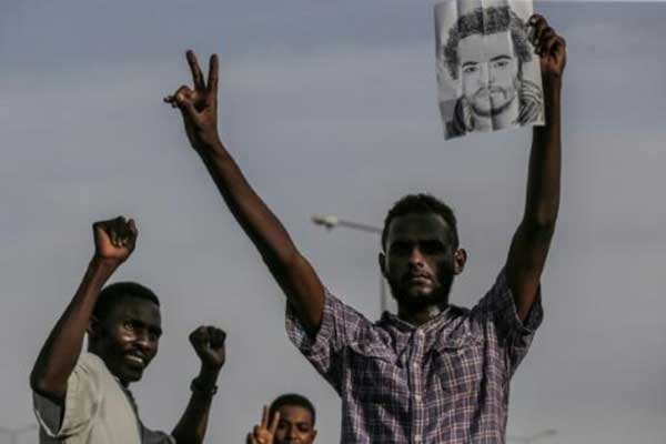 متظاهر سوداني يحمل صورة زميله الذي قتل في فضّ دامٍ لاعتصام أمام مقر قيادة الجيش في العاصمة خلال الشهر الفائت، في مسيرة لتأبين الضحايا في الخرطوم في 13 يوليو 2019