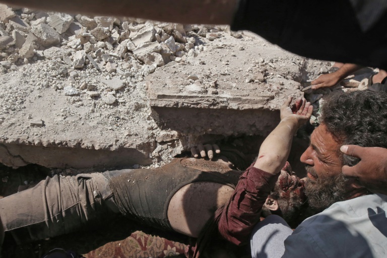 رجال يعملون على سحب جريح من تحت ركام مبنى استهدفته غارة جوية في 25 تموز/يوليو 2019 في بلدة كفررما قرب مدينة معرة النعمان في شمال غرب سوريا