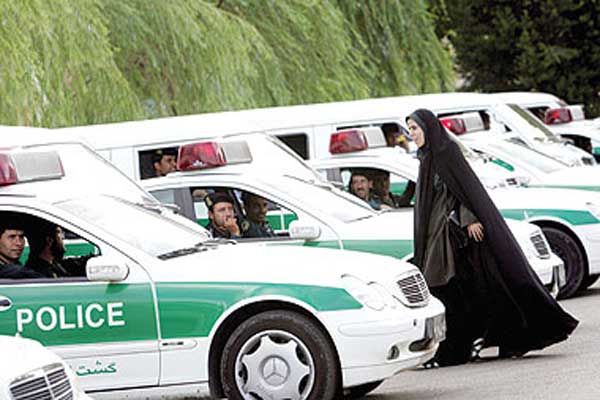  شرطية إيرانية تمر أمام سيارات للشرطة في طهران (أ.ف.ب)