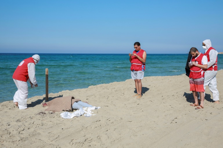عناصر من الهلال الاحمر الليبي قرب جثة احد المهاجرين على شاطئ الخمس شرق طرابلس الجعة في 26 تموز/يوليو 2019