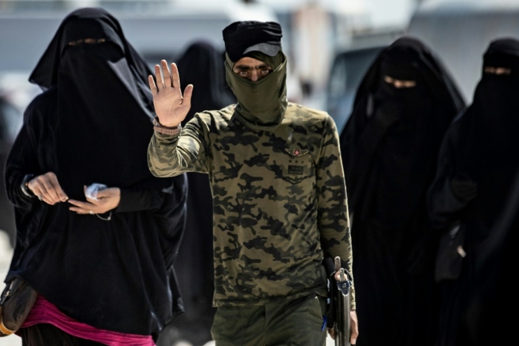 قوات أمنية ترافق نساء يعتقد انهن زوجات مقاتلي تنظيم داعش في مخيم الهول في محافظة الحسكة في شمال شرق سوريا