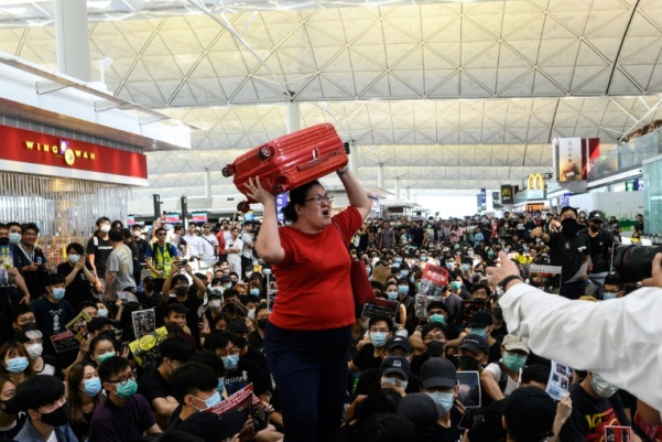مسافرة تصرخ حاملة حقيبتها أثناء محاولتها الدخول إلى باحة المغادرة في مطار هونغ كونغ الدولي أثناء تظاهرة جديدة في 13 أغسطس 2019