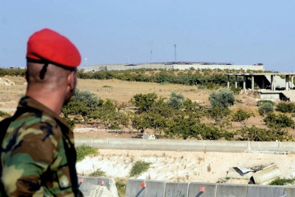 جندي في الجيش السوري ينظر في 24 أغسطس 2019 إلى نقطة المراقبة التركية المطوقة في بلدة مورك جنوب محافظة إدلب في شمال غرب سوريا
