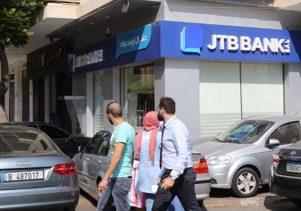لبنانيون يمرون بالقرب من فرع لمصرف جمّال تراست بنك في بيروت