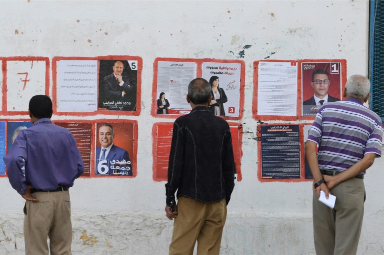 رجال ينظرون الى ملصقات للمرشحين للانتخابات الرئاسية التونسية في العاصمة في 2 سبتمبر 2019