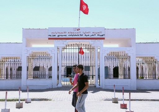 شابان يمران أمام المقر الجهوي لهيئة الانتخابات التونسية في مدينة سيدي بوزيد مهد الثورة