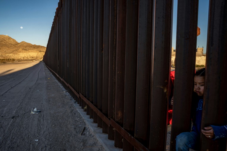 فتاة مكسيكية تقف عند الجدار المعدني الفاصل بين الولايات المتحدة والمكسيك في انابرا بولاية نيو مكسيكو الأميركية