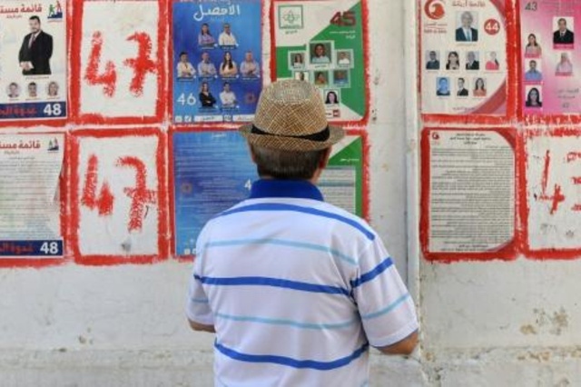 رجل تونسي ينظر إلى الملصقات الدعائية للمرشحين للانتخابات التشريعية في تونس العاصمة في 4 أكتوبر 2019