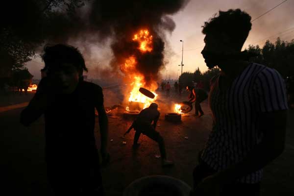 متظاهرون عراقيون يشعلون الإطارات خلال تظاهرات في بغداد بتاريخ 5 أكتوبر 2019