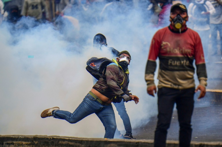 متظاهر يردّ قنبلة الغاز المسيل للدموع إلى الشرطة أثناء تظاهرة احتجاجاً على قرار الحكومة رفع أسعار الوقود في كيتو في 11 تشرين الأول/أكتوبر 2019