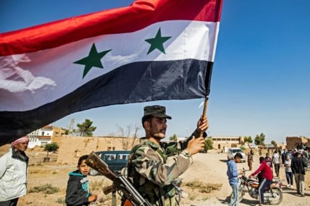 جندي سوري يحمل العلم السوري عند المدخل الغربي لبلدة تل تمر في محافظة الحسكة في شمال شرق سوريا في 14 أكتوبر