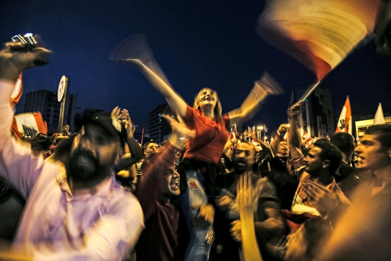 متظاهرون في مدينة طرابلس في شمال لبنان يهتفون خلال اعتصامهم ليلاً في ساحة النور في 22 تشرين الأول/أكتوبر 2019 في وقت تعم التظاهرات البلاد مطالبة برحيل الطبقة السياسية