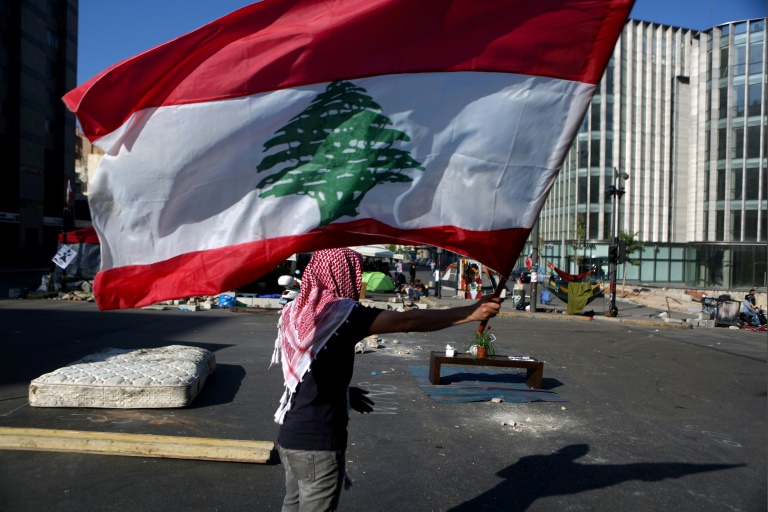 متظاهر لبناني يرفع العلم اللبناني في بيروت في 30 أكتوبر 2019