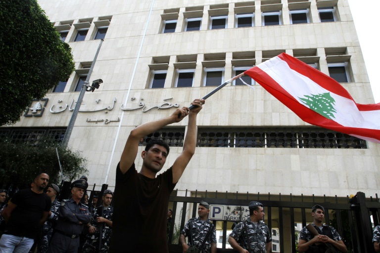 متظاهر يحمل العلم اللبناني خلال تظاهرة أمام المصرف المركزي فرع صيدا في جنوب لبنان