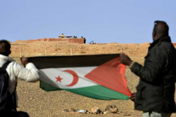 شخصان يرفعان علم جبهة البوليساريو في منطقة المحبس أمام جنود مغاربة - صورة أرشيفية
