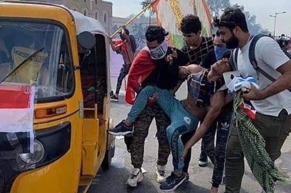 متظاهرون يسعفون زميلا مصابًا في بغداد