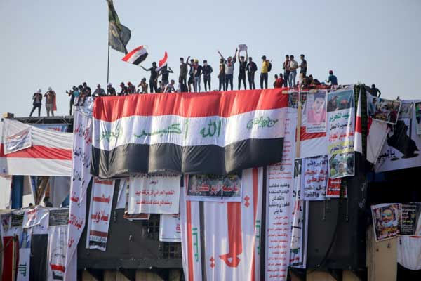 متظاهرو يتجمعون فوق مبنى مهجور في بغداد يطل على ساحة التحرير وجسر الجمهورية، السبت 2 نوفمبر 2019