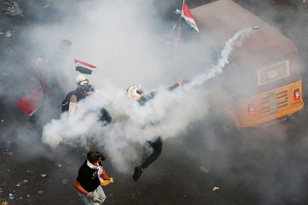 متظاهرون عراقيون يواجهون غاز القوات الأمنية المسيل للدموع