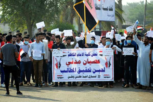 متظاهرون عراقيون يرفعون لافتة كتب عليها 
