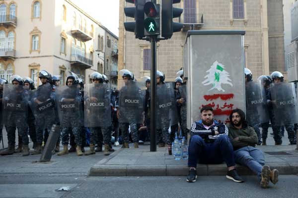 متظاهرون ضد الحكومة يجلسون على الرصيف في وسط بيروت في 4 نوفمبر 2019 وسط انتشار قوات الأمن
