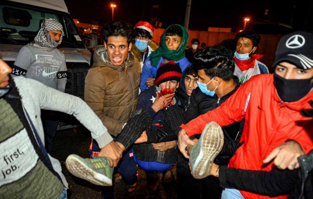 محتجون عراقيون يسعفون أحد المصابين في المواجهات مع قوات الأمن