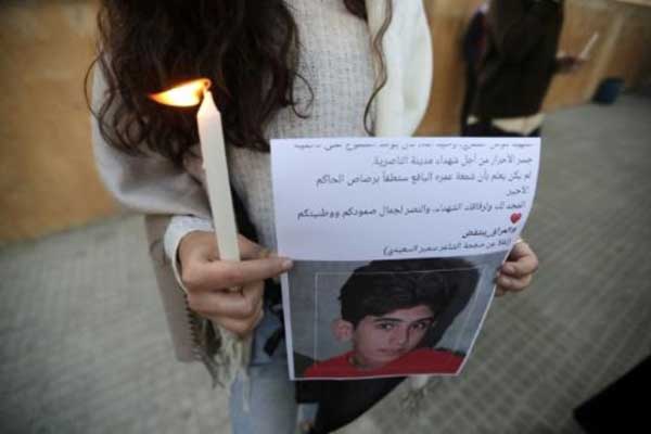 متظاهرة لبنانية ترفع صورة طفل عراقي قتل خلال التظاهرات خلال مشاركتها في الاعتصام أمام السفارة العراقية في بيروت، في 30 نوفمبر 2019