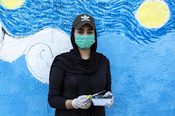 منة الله محمد، رسامة عراقية في الثانية والعشرن تقف أمام لوحة جدارية رسمتها خلال تظاهرة مناهضة للحكومة في مدينة البصرة الجنوبية في 27 نوفمبر 2019
