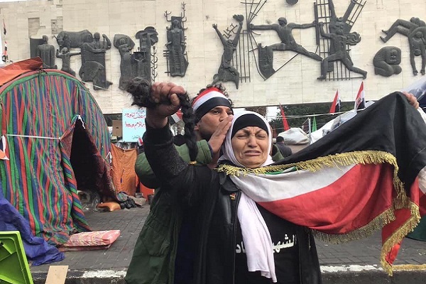 أم عراقية تقص ظفيرتها حزنا على شهداء الاحتجاجات الشباب