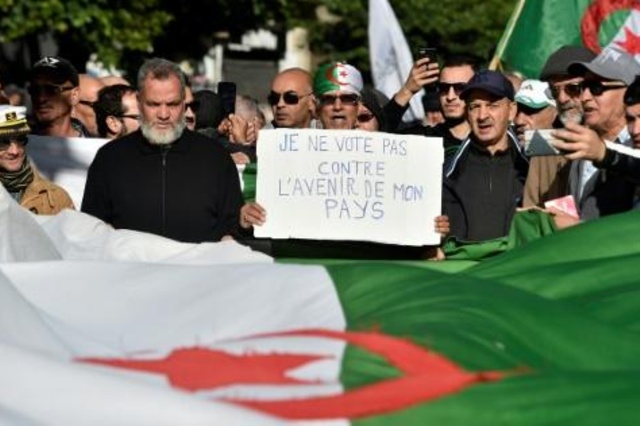 محتجون جزائريون يسيرون حاملين أعلاماً وطنية ولافتات أثناء تظاهرة معارضة للانتخابات الرئاسية في العاصمة الجزائر